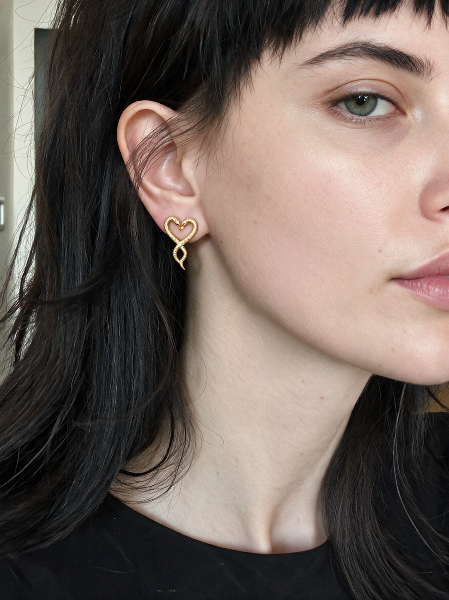 Model with a dark fringe wearing the Serpent Heart Earrings in 18K gold vermeil
