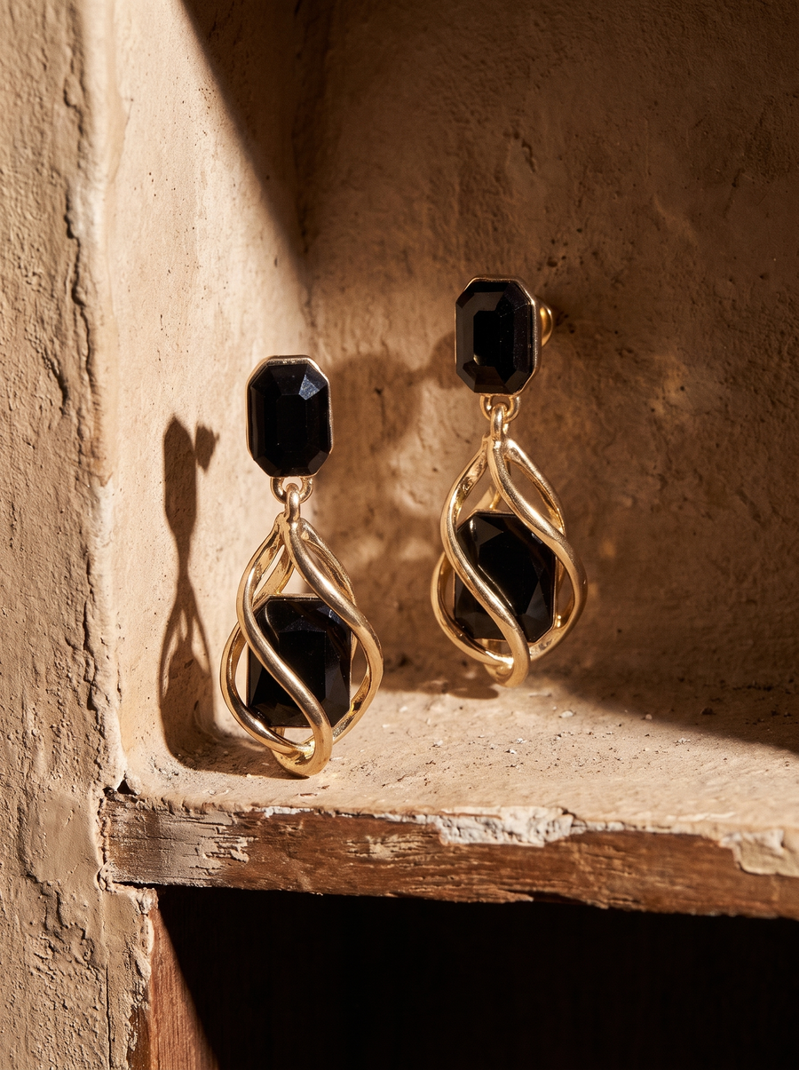 Black Wrap Earrings in 18K gold vermeil with black stones, displayed in a sunlit plaster alcove