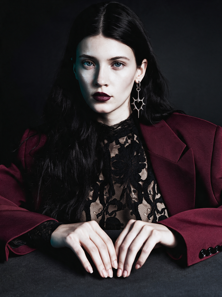 Model in a burgundy blazer and black lace wearing the Thorn Heart Earrings in oxidised silver