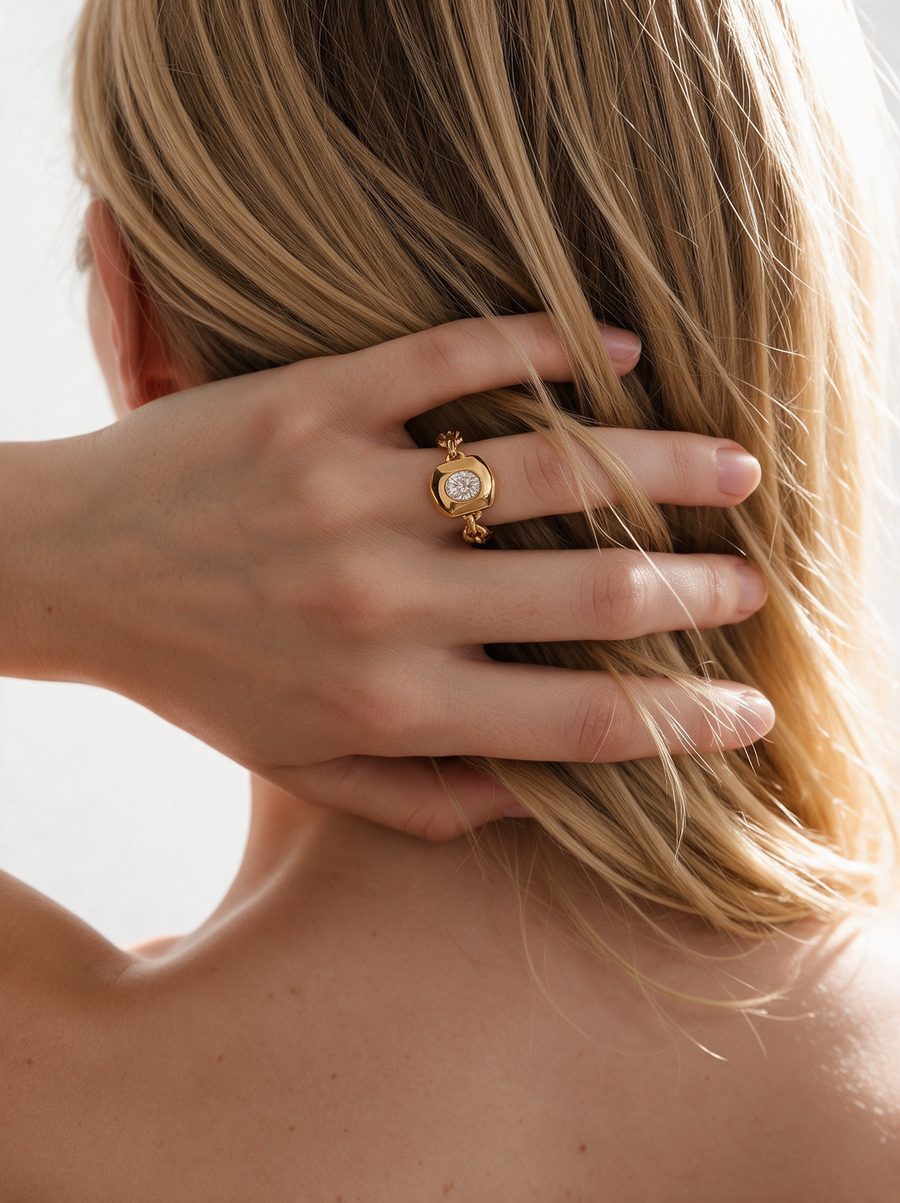 Model wearing the Chain Ring in 18K gold vermeil with a white stone, hand in her hair