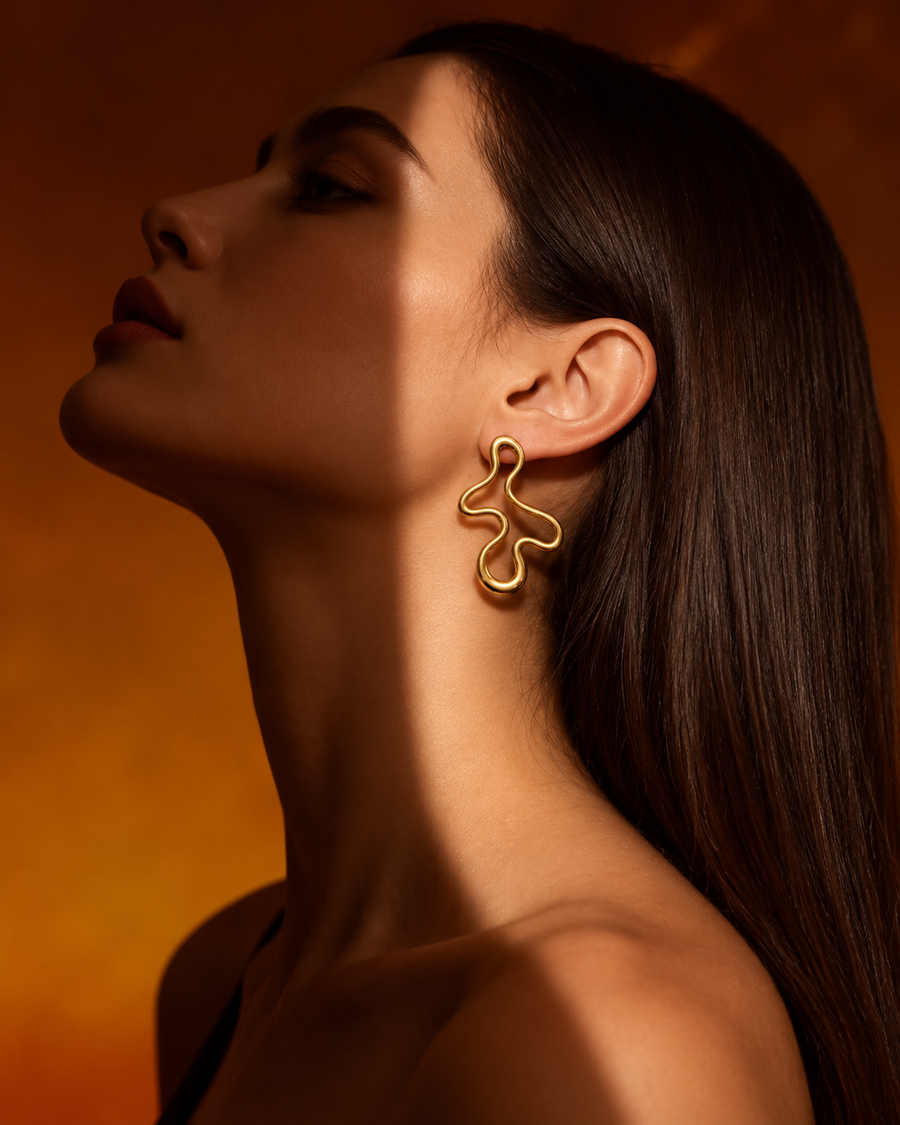 Model in profile wearing the Doodle Studs in 18K gold vermeil against a warm amber backdrop