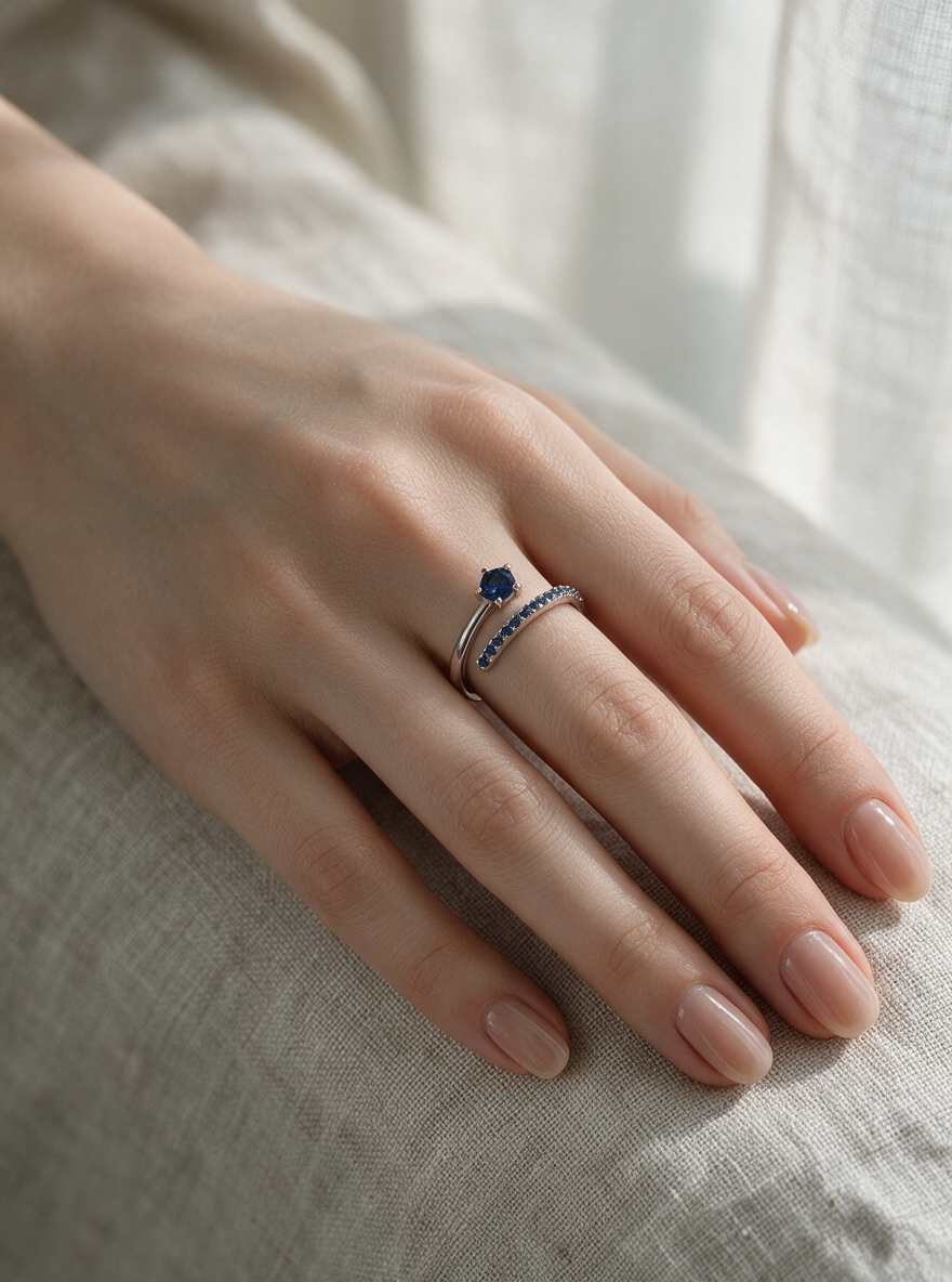 Comet Ring in sterling silver with blue stones on a hand resting on white linen
