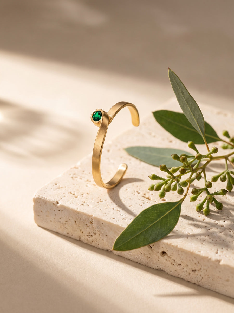 Curl Ring in 18K Gold Vermeil with a green stone on travertine