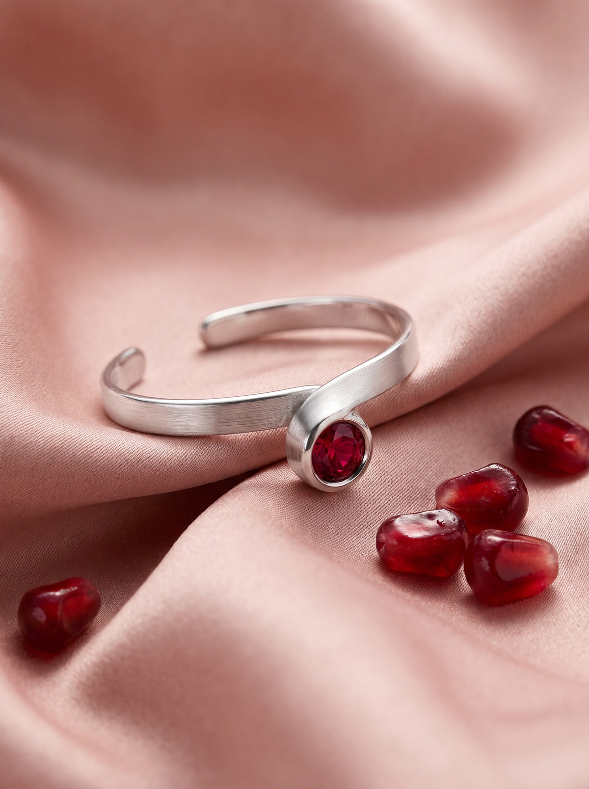Curl Ring in Sterling Silver with a red stone on blush silk