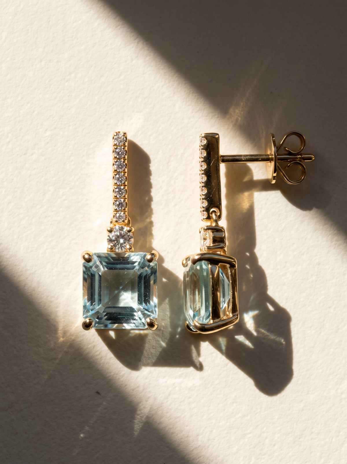 Ice Drop Earrings in 18K gold vermeil with light blue square-cut stones in raking sunlight