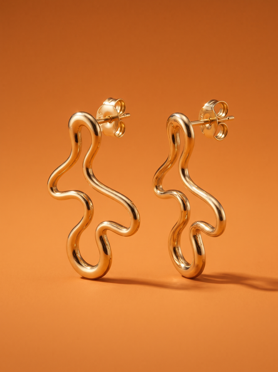 Doodle Studs in 18K gold vermeil, freehand squiggle earrings against a burnt-orange backdrop