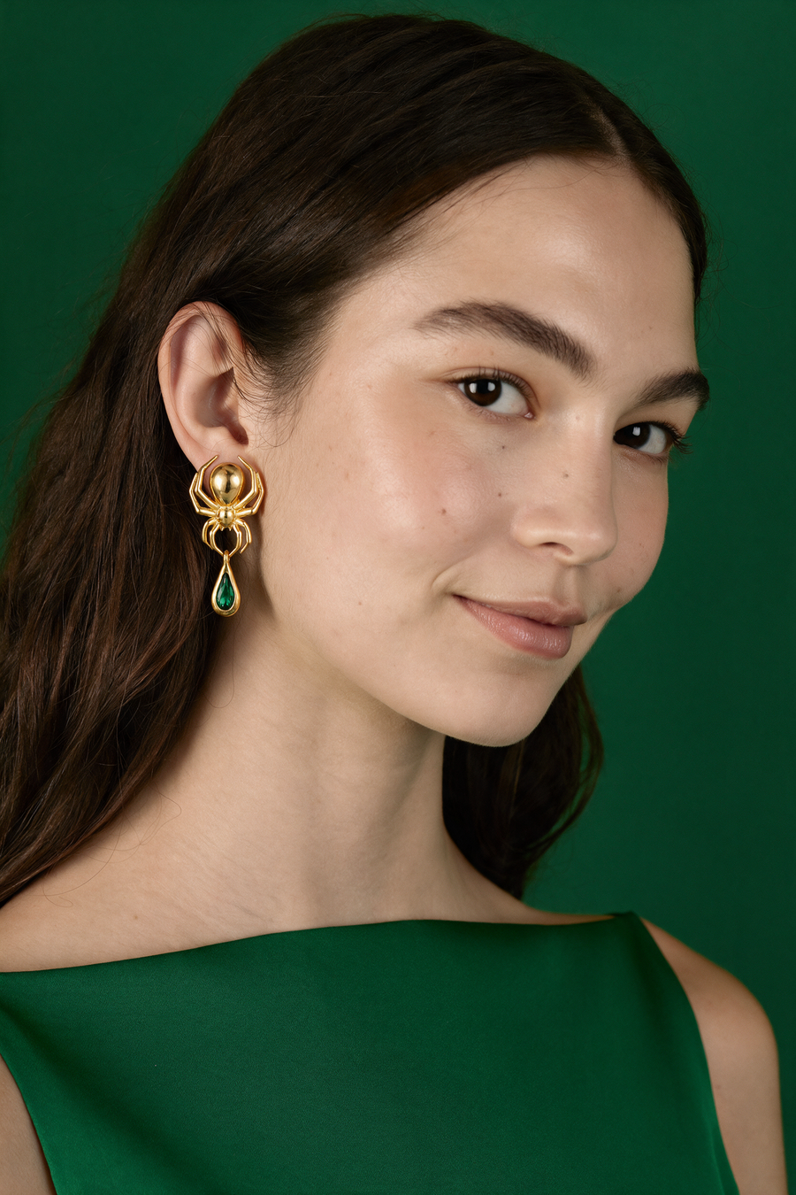 Model in green wearing the Spider Earrings in 18K gold vermeil with a green stone