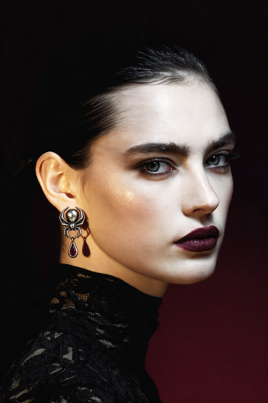 Model in black lace wearing the Spider Earrings in oxidised silver with a red stone