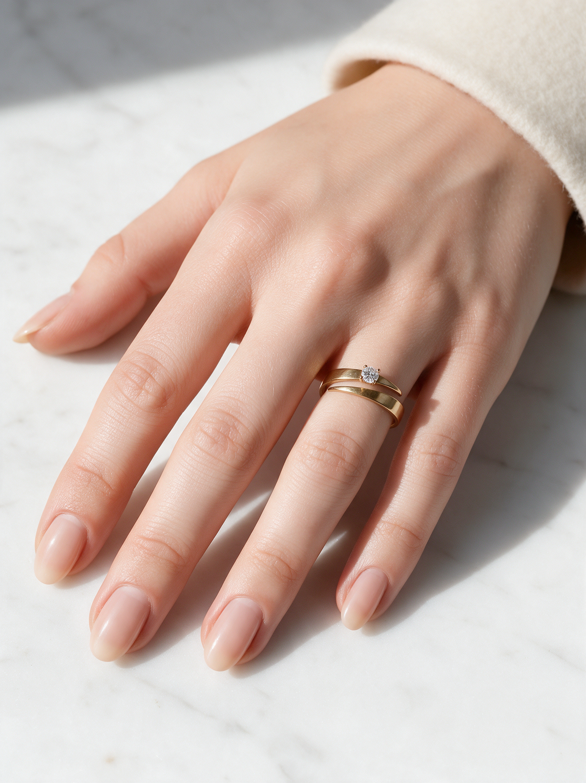Tier Ring in 18K gold vermeil with a white stone on a hand resting on white marble