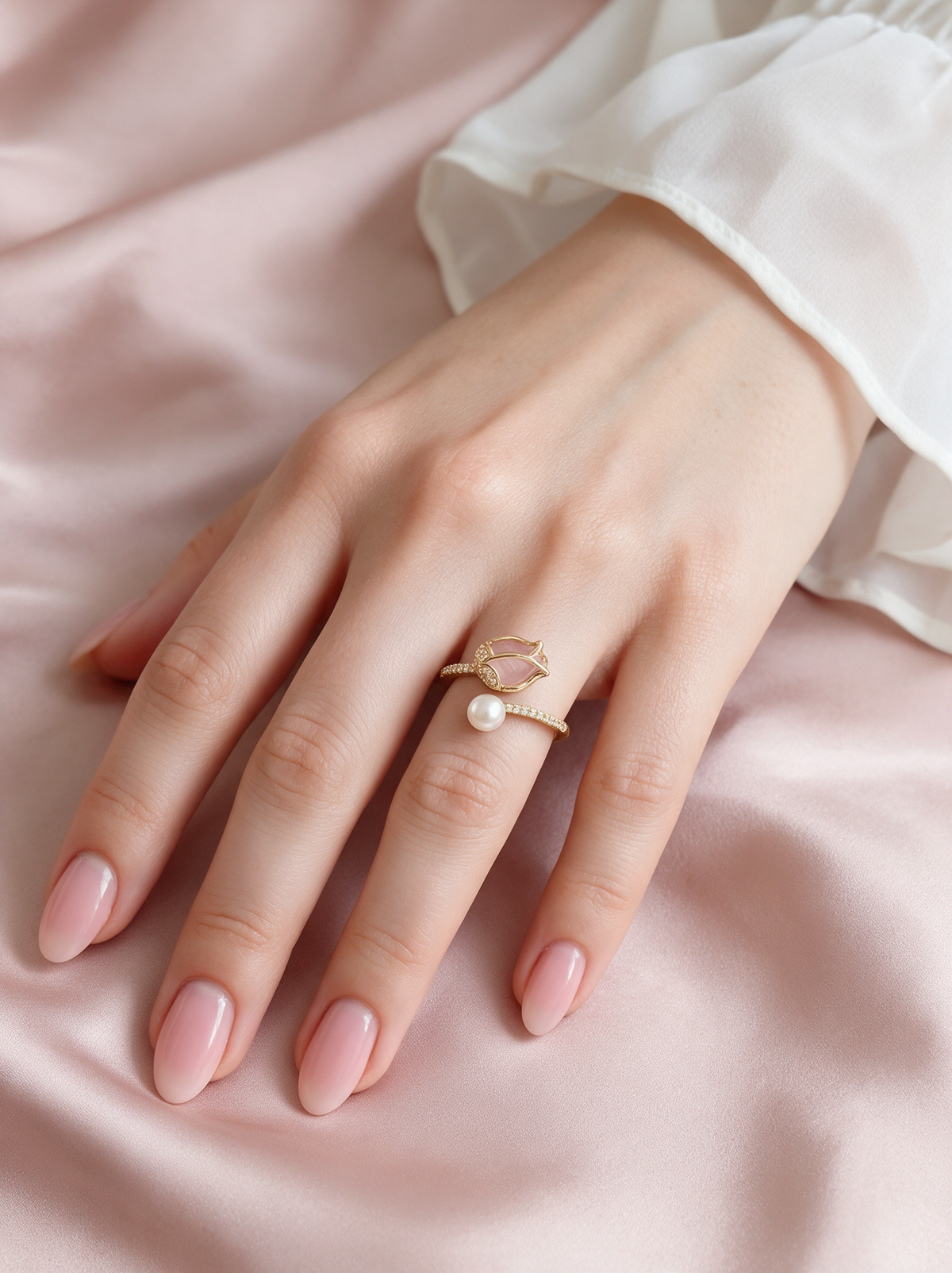 Calyx Ring worn on a hand resting on blush satin