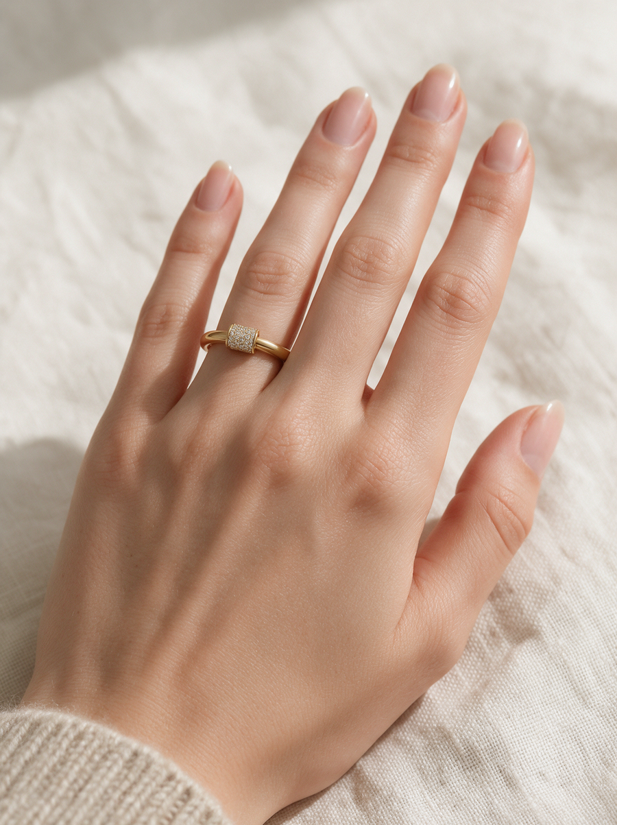 Lock Ring in 18K gold vermeil with white stones on a hand resting on a cream knit throw
