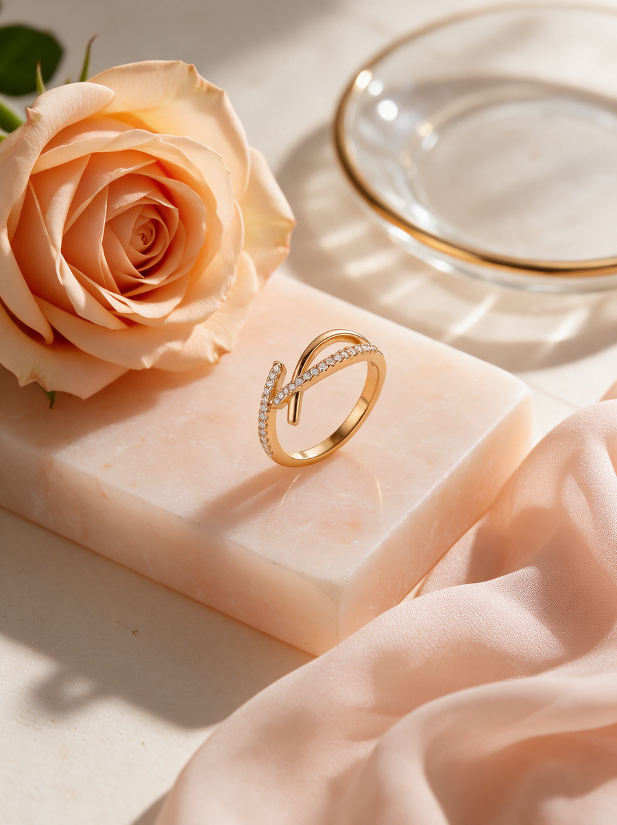 Tangent Ring in 18K gold vermeil on a blush stone block beside a peach rose and silk