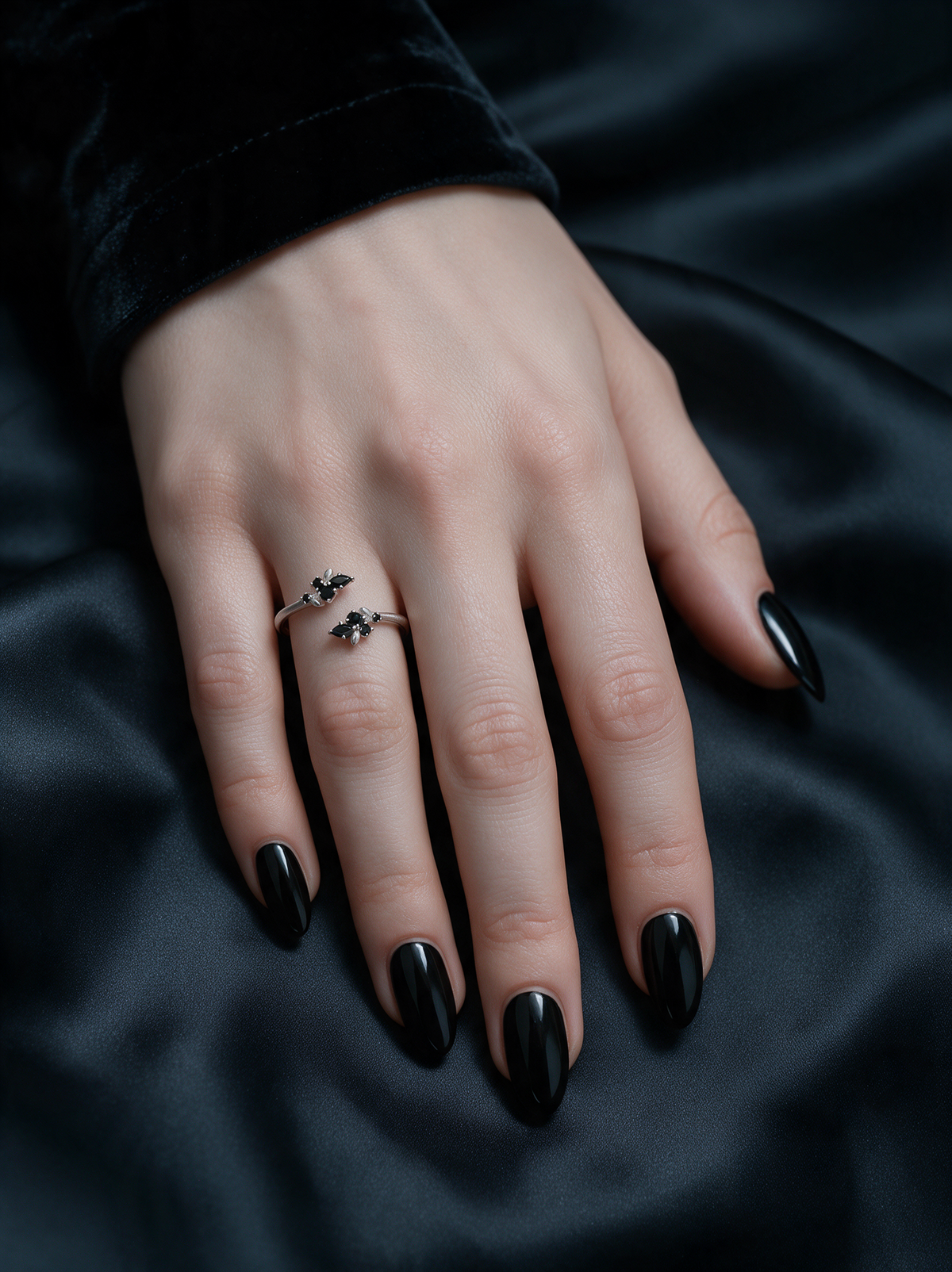 Bloom Ring in sterling silver with black stones on a hand with black nails, resting on black satin