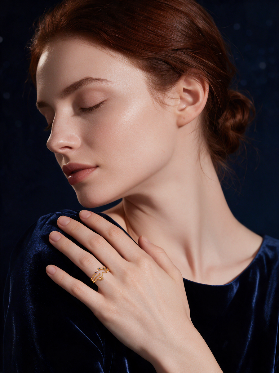 Model in navy velvet, eyes closed, wearing the Cosmic Ring in 18K gold vermeil with blue stones