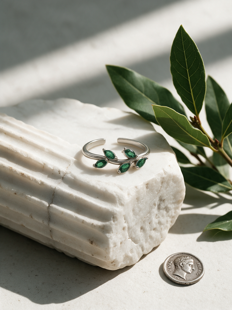 Laurel Ring in sterling silver with green marquise stones on a fluted marble fragment beside bay leaves