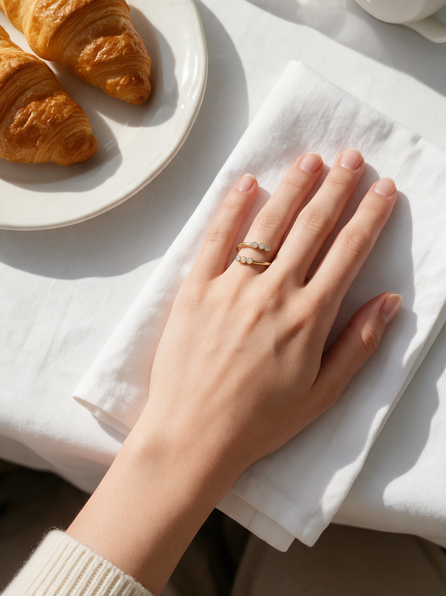 Twin Trail Ring in 18K gold vermeil with white stones on a hand on a white napkin beside croissants