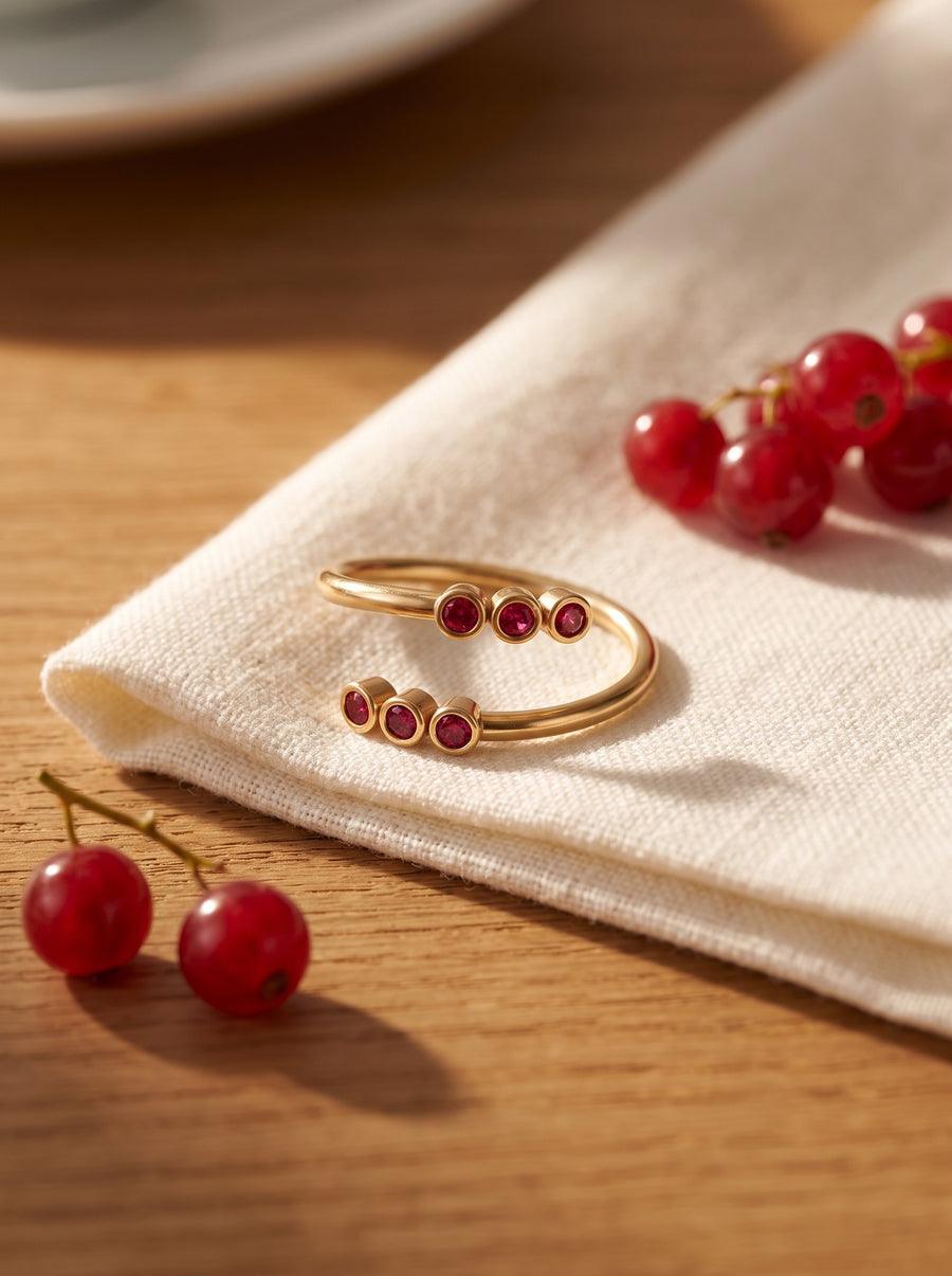 Twin Trail Ring in 18K gold vermeil with red stones on an ivory linen napkin beside red currants